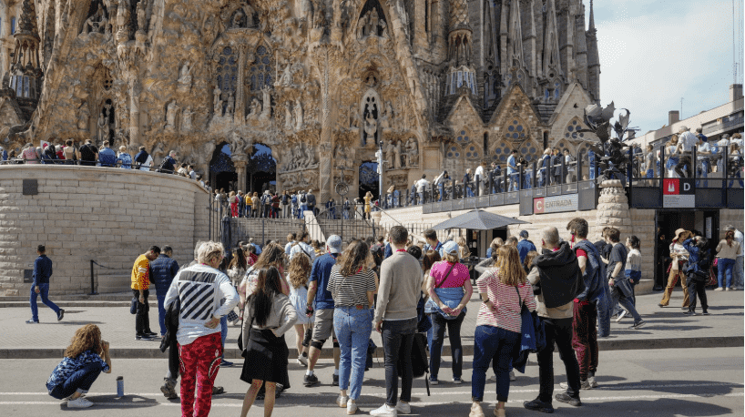 Turistas hacen fila para ingresar a la Sagrada Familia en Barcelona, uno de los monumentos más visitados de Europa. La postal ilustra el desafío de equilibrar la afluencia masiva con la preservación patrimonial y la calidad de vida urbana.